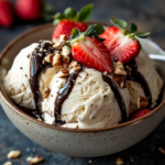 Keto ice cream served in a bowl with strawberries, nuts, and sugar-free chocolate syrup